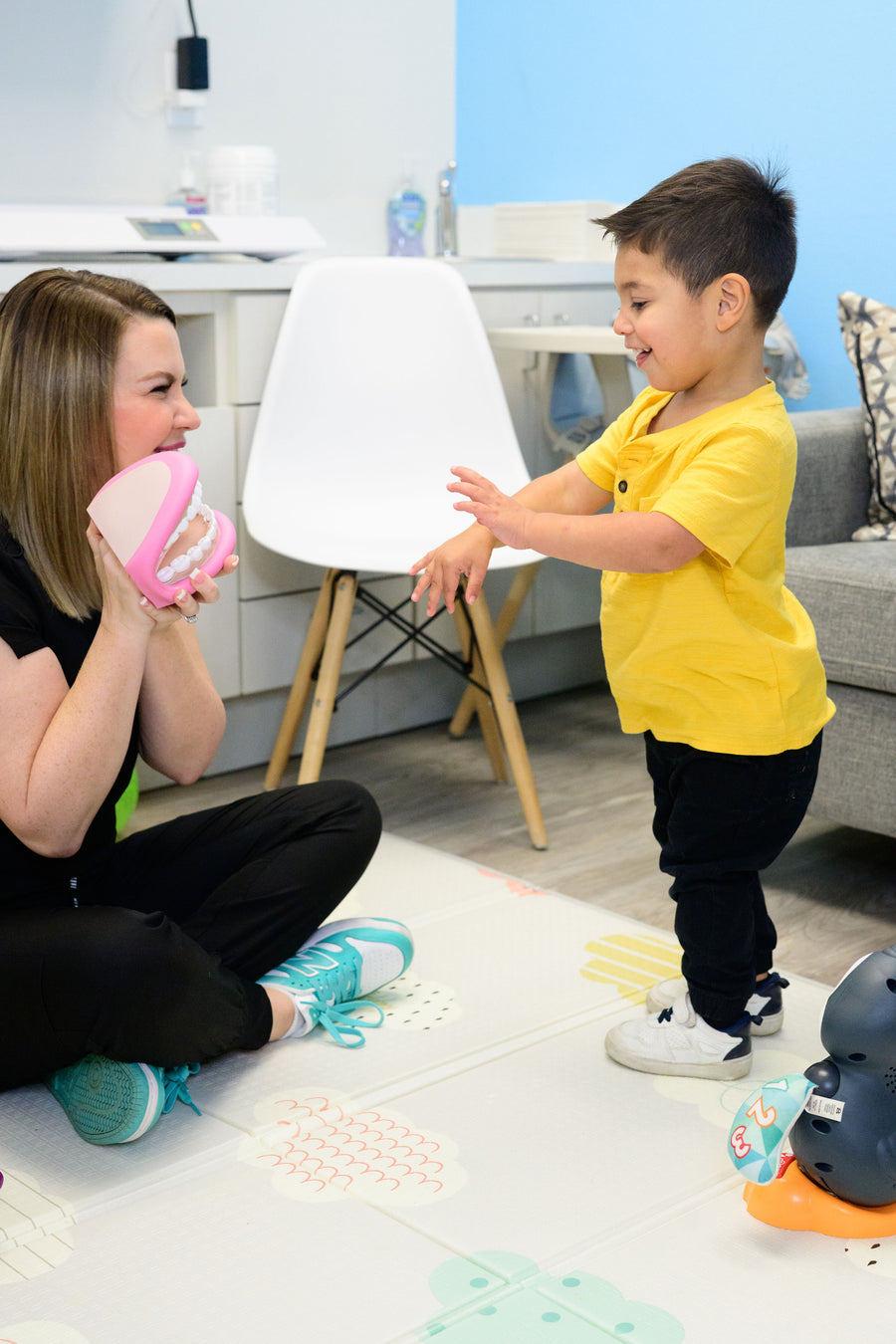 Meagan playing with a toddler using a large mouth model during therapy